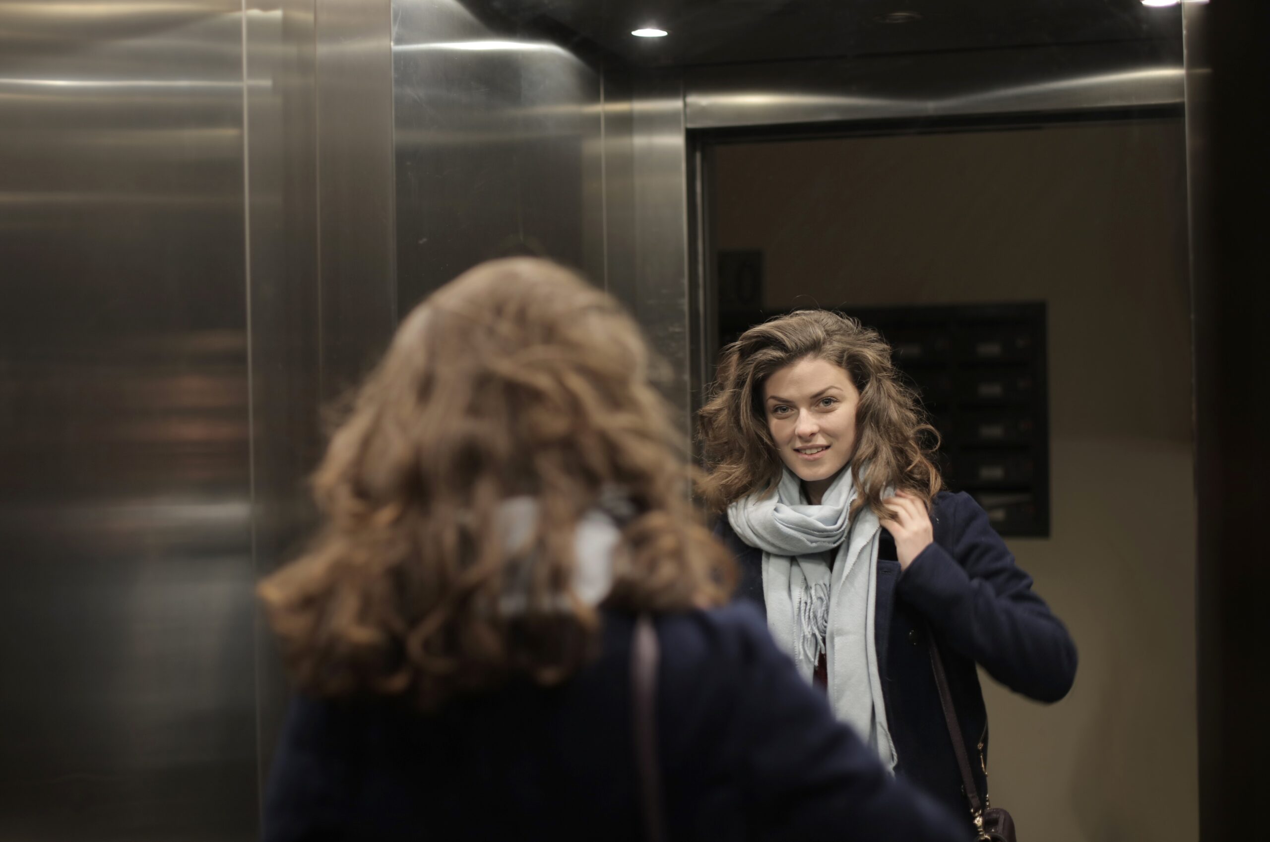 Woman looking at her mirrored reflection in an elevator